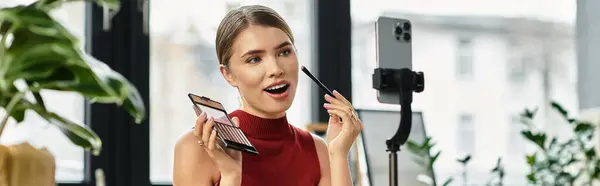Jolie jeune femme démontre des produits de beauté tout en streaming sur son smartphone à la maison, bannière — Photo de stock