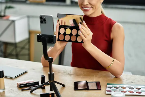 Una joven influenciadora comparte sus productos de belleza favoritos en una transmisión en vivo desde su espacio de trabajo. - foto de stock