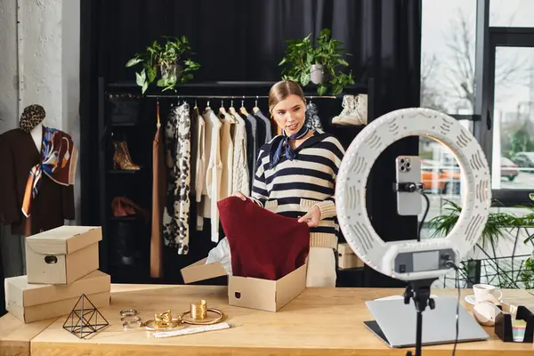 Mujer joven selecciona ropa elegante mientras filma sus consejos de moda para seguidores en un estudio elegante. - foto de stock
