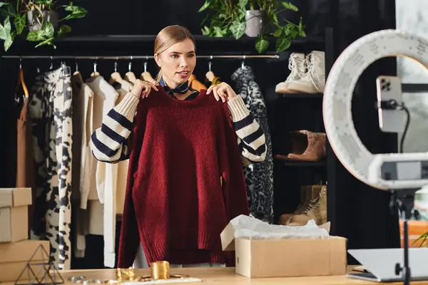 Influenciador atraente organiza itens de roupas elegantes enquanto grava em seu smartphone. — Fotografia de Stock