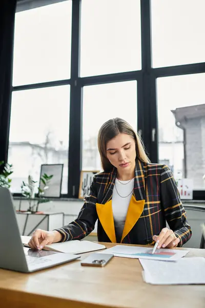 A young businesswoman reviews documents at a sleek office desk, focused on her work. — Stock Photo