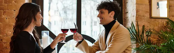 A couple clinks glasses of red wine, enjoying a romantic evening celebrating their love, banner — Stock Photo