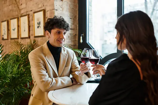 A joyful couple toasts with wine glasses, embracing their love at a cozy restaurant. — Stock Photo
