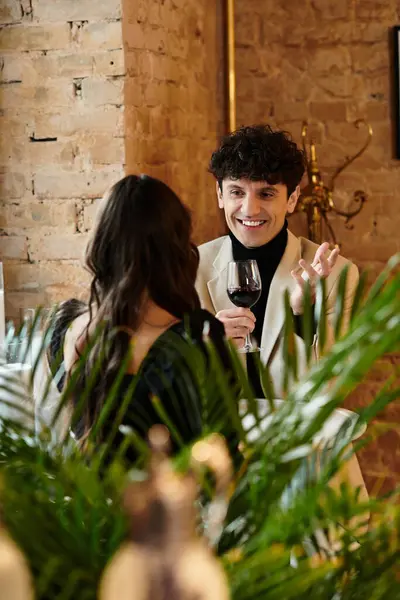 A couple enjoys a romantic dinner, laughing and sharing a glass of wine at a cozy restaurant. — Stock Photo