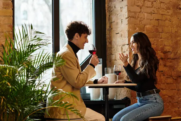 Couple shares laughs and wine, celebrating their love in an intimate restaurant atmosphere. — Stock Photo