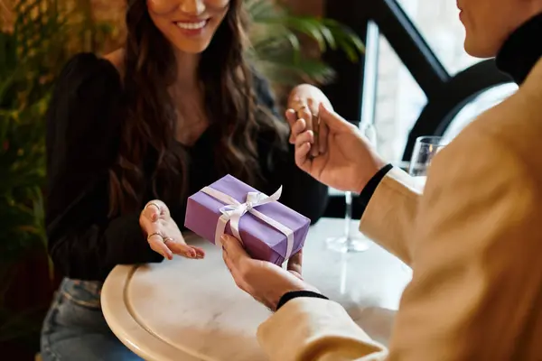 A couple celebrates their love with a thoughtful gift in a romantic restaurant. — Stock Photo