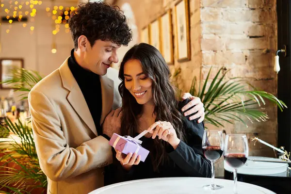A young couple shares a heartfelt moment while exchanging gifts in a charming restaurant. — Stock Photo