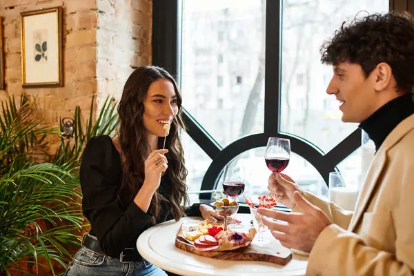 A happy couple enjoys a romantic meal with wine, celebrating their love in a cozy spot. — Stock Photo