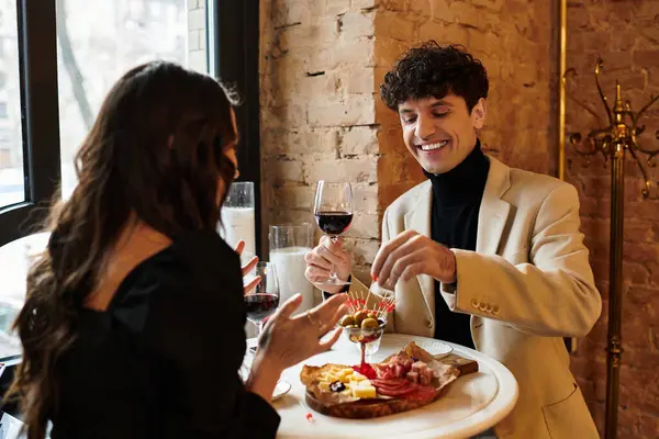 A couple enjoys a romantic dinner, sharing food and laughter while celebrating their love. — Stock Photo