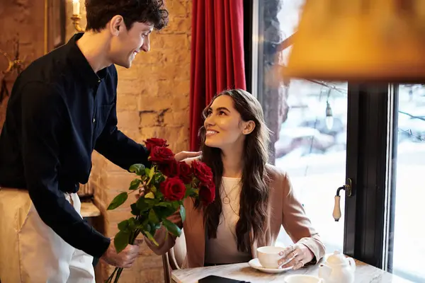A young couple enjoys a special moment together, sharing smiles and flowers in a cozy restaurant. — Stock Photo