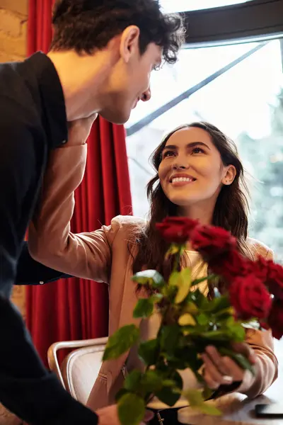 A young couple exchanges smiles while enjoying Valentines Day in an intimate setting with roses. — Stock Photo