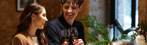 A young couple enjoys a romantic dinner, toasting with glasses of red wine on Valentines Day, banner — Stock Photo