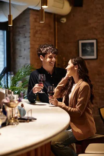 A young couple enjoys a romantic evening, toasting with glasses of wine in a charming restaurant. — Stock Photo