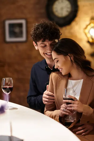 A young couple shares a joyful moment over drinks, celebrating their love in a romantic setting. — Stock Photo