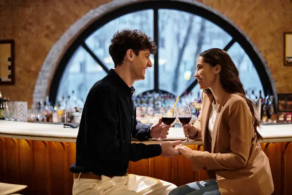 A joyful couple enjoys their romantic dinner, sharing drinks and loving glances. — Stock Photo