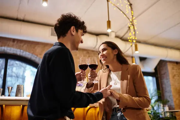 A beautiful young couple celebrates love with drinks while embracing in an intimate restaurant. — Stock Photo