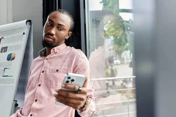 A young man concentrates on his smartphone while working casually in a bright, stylish office. — Stock Photo