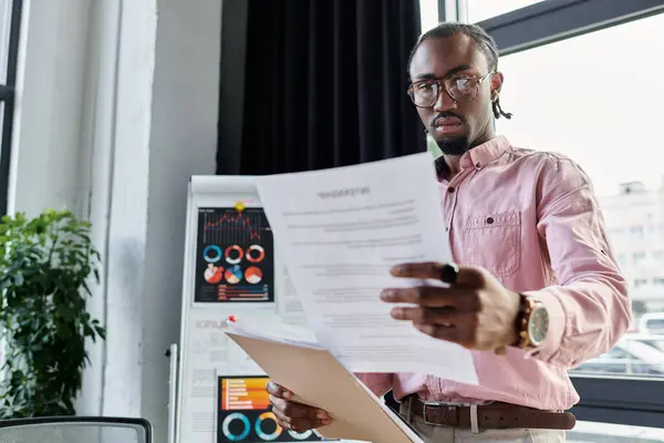 Focused young man reviews important documents in a vibrant workspace during the day. — Stock Photo