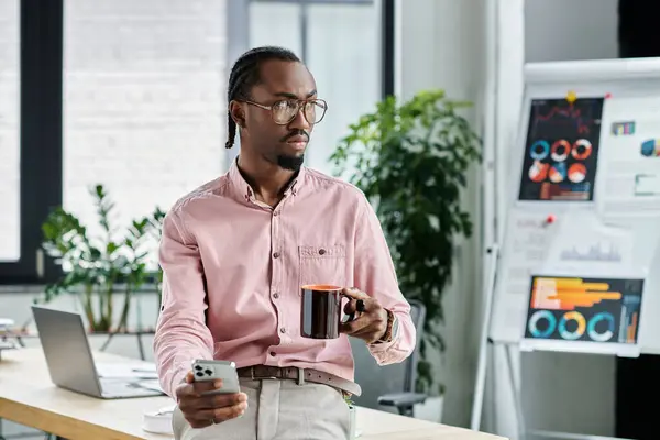 A young african american man balances work and relaxation in a stylish office, sipping coffee. — Stock Photo