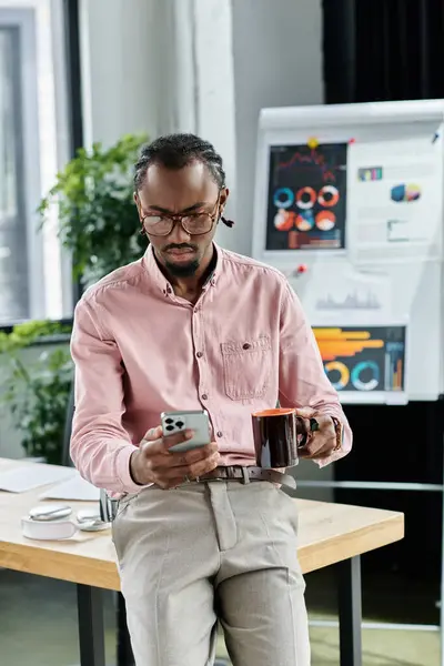 Engaged in work while enjoying a warm drink, a young man relishes remote life in a bright office. — Stock Photo