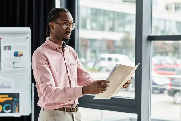 Focused young man reviewing documents in a bright, modern workspace while remote working. — Stock Photo