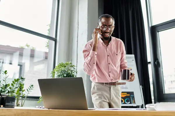 Engaged in a phone conversation while enjoying a coffee, a young man embraces remote work. — Stock Photo