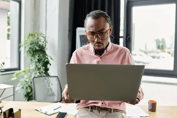 Young African American man works intently on his laptop in a vibrant coworking environment. — Stock Photo