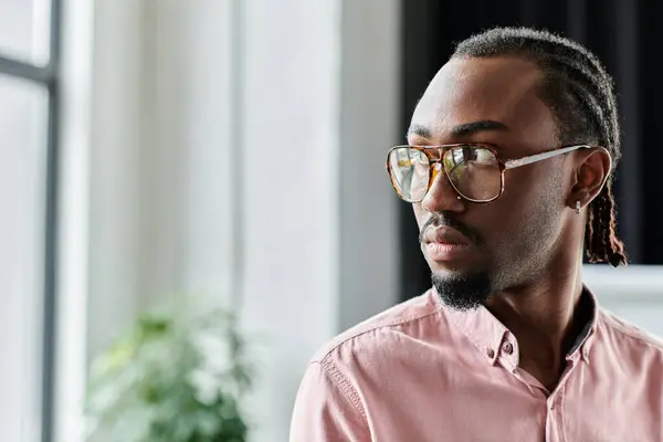 Focused young man in stylish glasses works in a bright, contemporary workspace filled with greenery. — Stock Photo