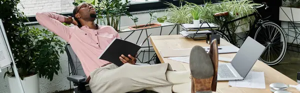 A young african american man relaxes in a chic urban office, enjoying his nomadic lifestyle. — Stock Photo