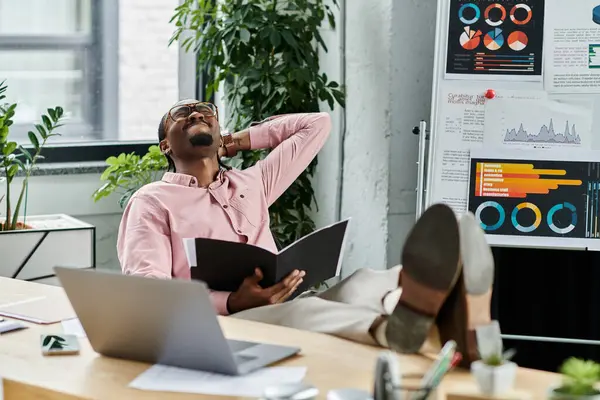 Un joven guapo se relaja mientras revisa documentos en un espacio de trabajo brillante y moderno. - foto de stock