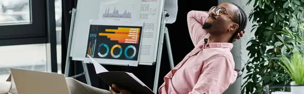 Focused young man reviews his work while relaxing in a contemporary office setting. — Stock Photo