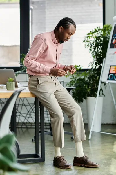 Focused young man adjusts his glasses while seated in a bright, stylish office setting. — Stock Photo