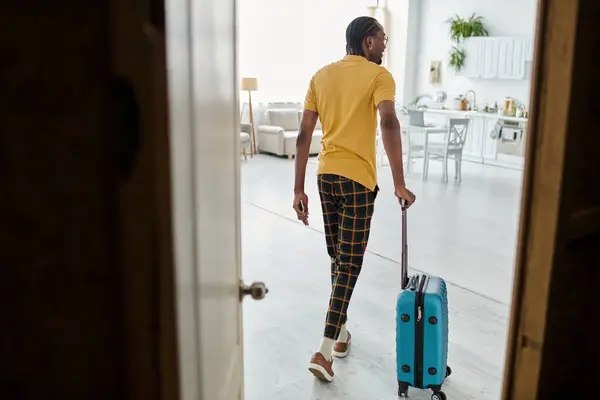 A stylish young man grabs his suitcase, ready to leave his apartment for an adventure. — Stock Photo