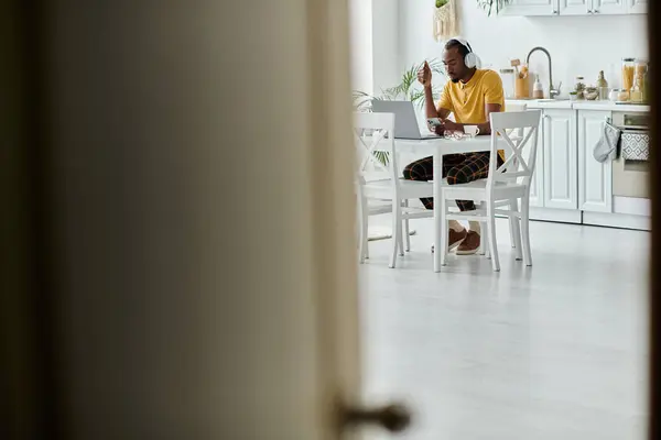 Focused young man engages with his laptop in a stylish kitchen, embracing remote work freedom. — Stock Photo