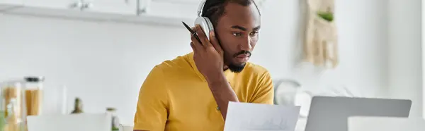 A handsome young man engages in remote work from his well lit home office, showcasing nomadic life. — Stock Photo