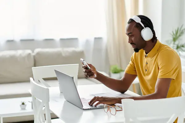 El hombre se centra en el trabajo mientras se mantiene conectado a través de su teléfono en un ambiente brillante y moderno. - foto de stock