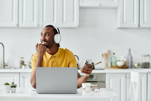 Un joven afroamericano inmerso en su trabajo remoto con auriculares puestos, sonriendo felizmente. - foto de stock