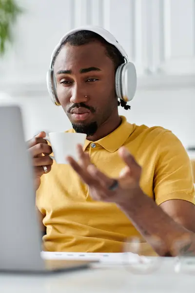 A young african american man savors coffee while engaged in remote work at his stylish workspace. — Stock Photo
