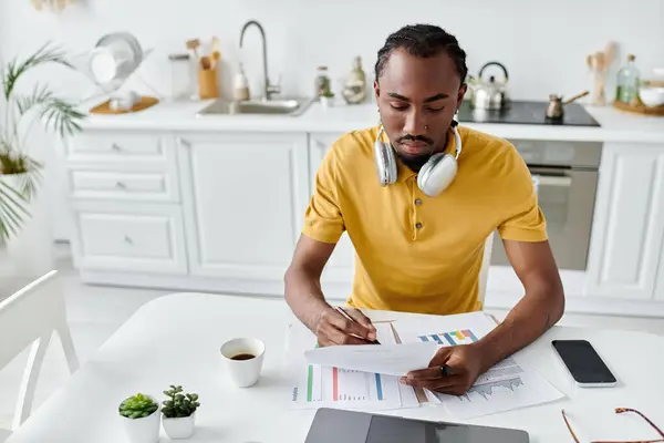Young man focuses on his work while enjoying a cup of coffee in a modern kitchen. — Stock Photo