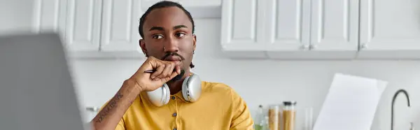 Young african american man using laptop while thoughtfully observing his surroundings at home — Stock Photo
