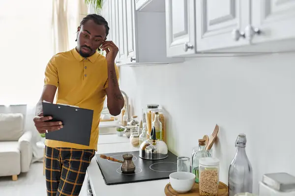 Digital nomad engaged in work from home, balancing tasks in a modern kitchen setting. — Stock Photo