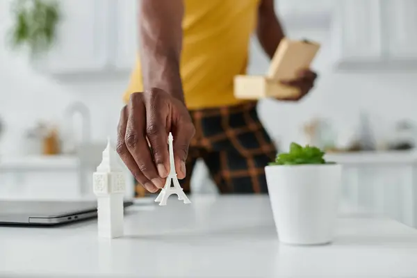 Um jovem bonito organiza marcos em miniatura enquanto trabalha remotamente em um espaço brilhante. — Fotografia de Stock