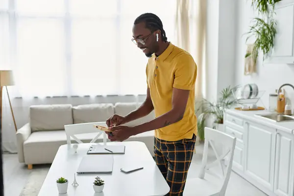Digital nomad immersed in work, using a smartphone while standing at a stylish desk. — Stock Photo