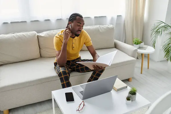This young man actively balances work and learning in a modern, inviting living room. — Stock Photo