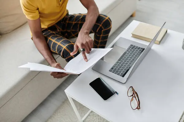 Focused young man engages with documents while working remotely in a relaxed setting. — Stock Photo