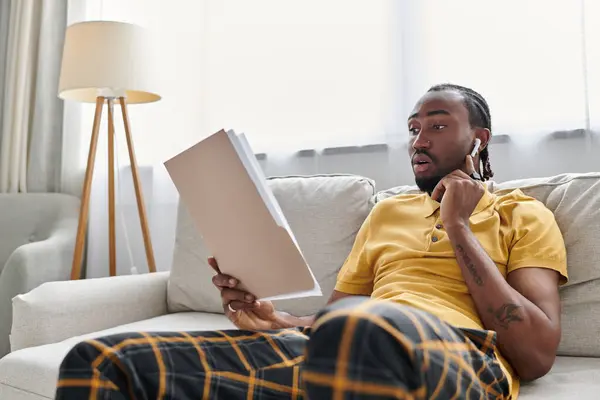 African American man engages in digital nomad lifestyle, reviewing documents at home. — Stock Photo