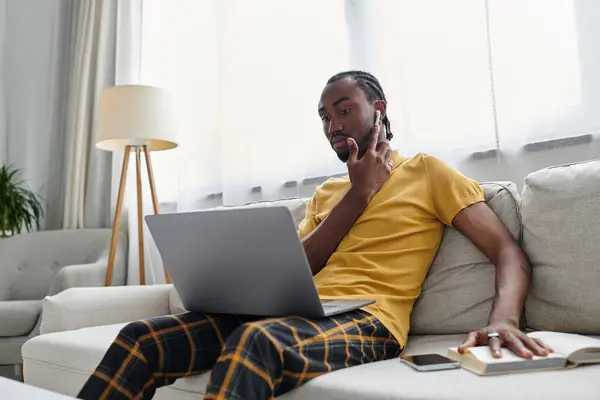 Hombre afroamericano enfocado comprometido en el trabajo digital en su espacio de vida moderno. - foto de stock