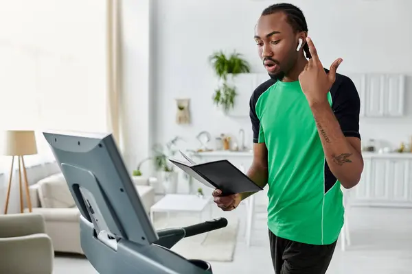 Ein junger afrikanisch-amerikanischer Mann multitasks auf einem Trainingsgerät während der Teilnahme an Arbeitsaufgaben. — Stockfoto