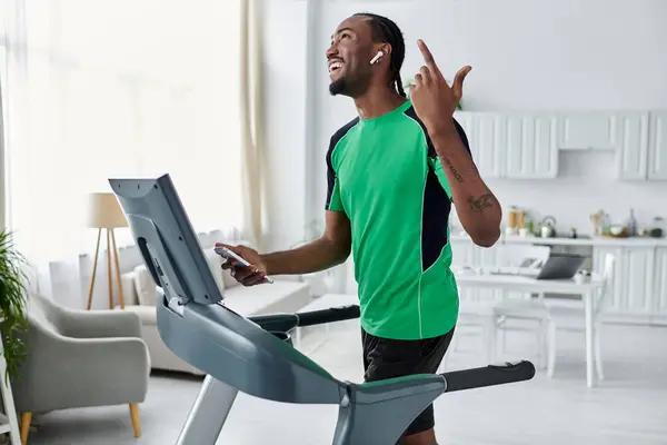 A young African American man smiles and moves to the rhythm of music while exercising indoors. — Stock Photo