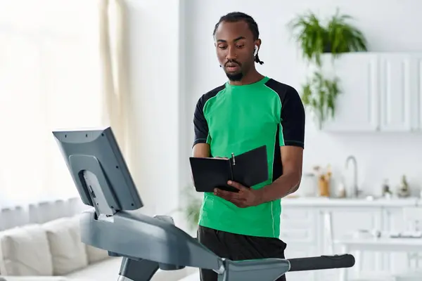 A young man balances workout and productivity, taking notes while exercising in a sunlit room. — Stock Photo